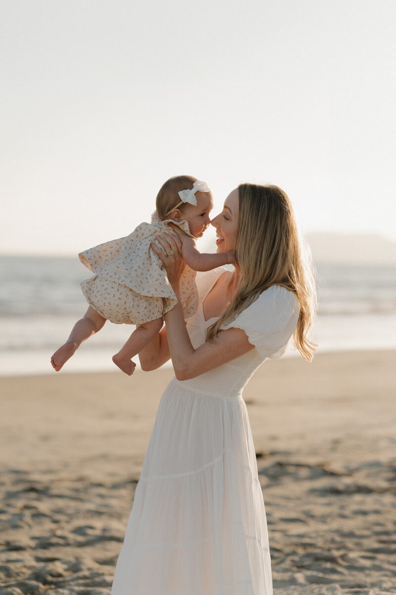 New Mom holds her baby during a sunset family session at coronado beach in San Diego